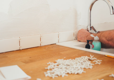 Man placing tile spacers between backsplash tiles