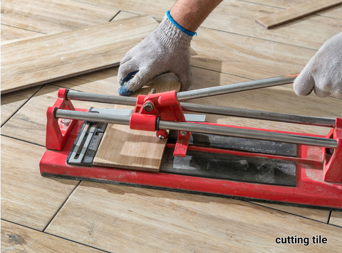 A person cutting a luxury vinyl tile with a tile cutter