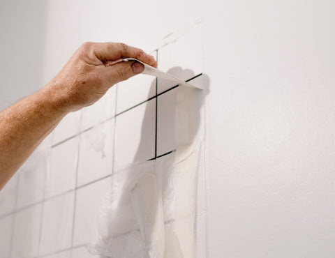 Man removing tile from shower